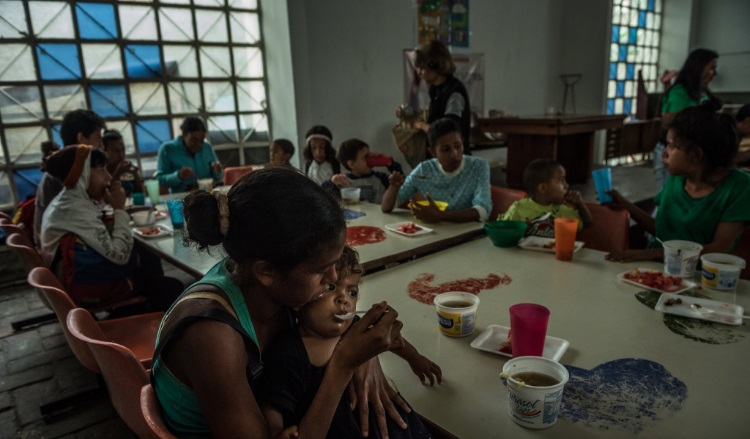 María Tocuyo, 28, feeding her 1-year-old daughter at a soup kitchen. Credit Meridith Kohut for The New York Times